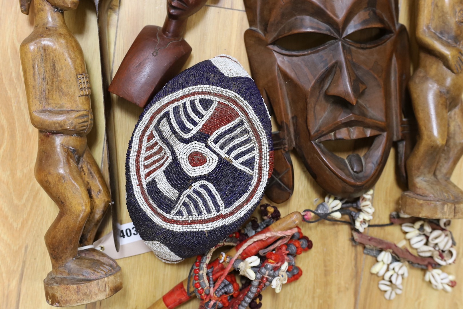 A group of African hardwood carvings, shell and beadwork including a cap